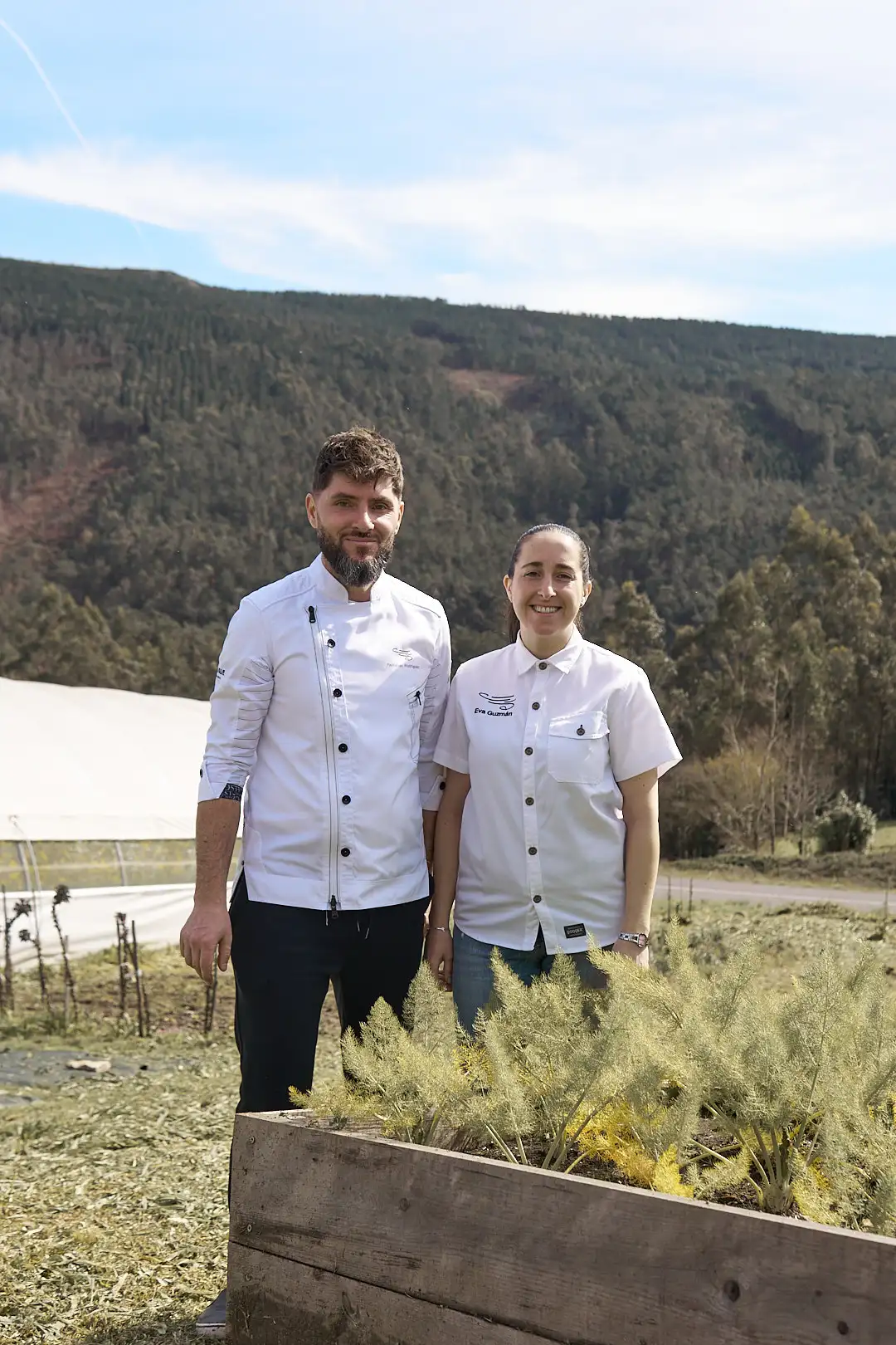Los 2 dueños del restaurante secadeiro en una foto con el invernadero de fondo y ellos con sus trajes de cocineros